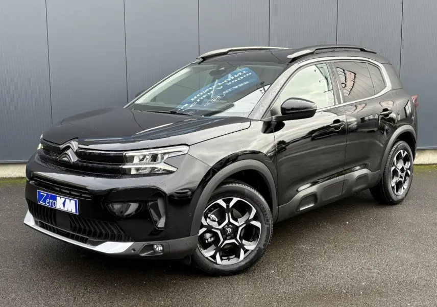 Vue 3/4 avant droite d'un Citroën C5 Aircross noir Perla avec jantes alliage bi-ton et barres de toit noires.