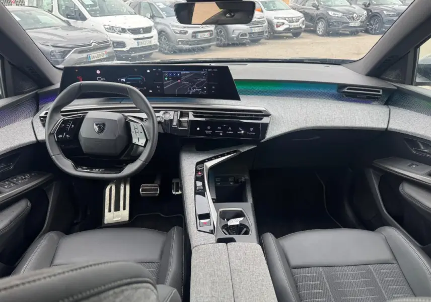 Intérieur moderne du Peugeot 5008 Hybrid noir, vue avant centrée sur le volant et le cockpit numérique large.