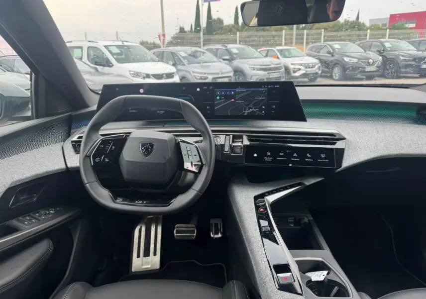 Vue intérieure avant du Peugeot 5008 Hybrid noir 2025, avec volant compact, écran numérique large et console centrale design.