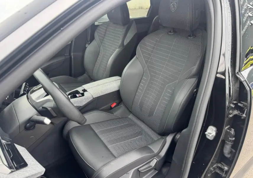 Vue intérieure côté conducteur du Peugeot 5008 Hybrid noir, siège sport avec logo Peugeot brodé sur l'appuie-tête.