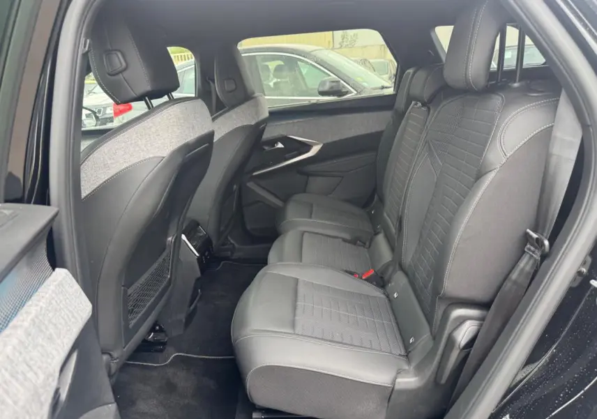Vue intérieure côté droit des sièges arrière en cuir noir et tissu gris du Peugeot 5008 Hybrid 2025 avec appuie-têtes et ceintures visibles.