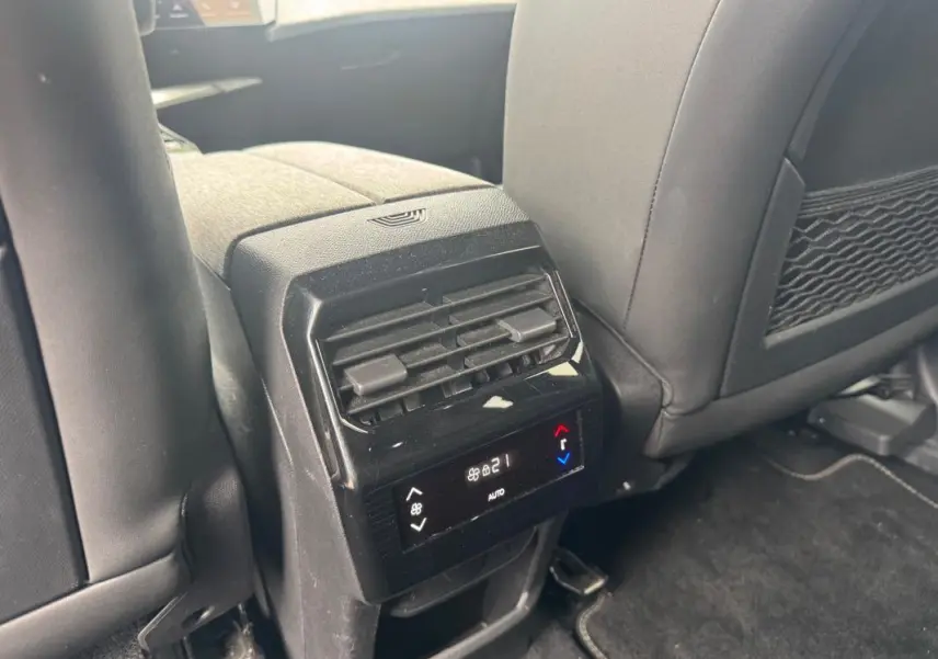 Vue rapprochée de la console arrière noire du Peugeot 5008 Hybrid 145 ch avec commandes de climatisation digitale.