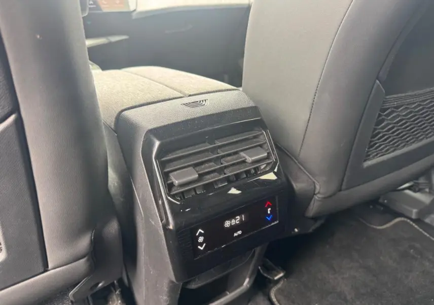 Vue rapprochée de la console centrale arrière du Peugeot 5008 noir, avec commandes climatisation digitale et sièges en cuir gris.