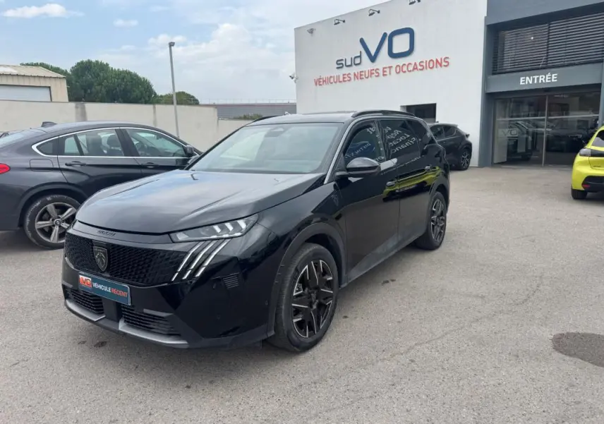 Peugeot 5008 Hybrid noir en 3/4 avant droit, avec jantes alliage 19 pouces et barres de toit visibles.