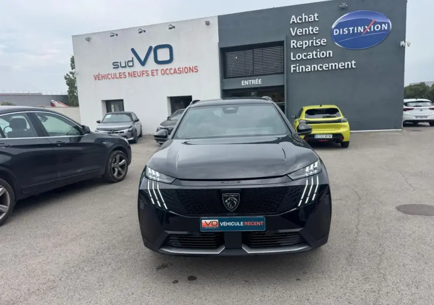 Vue de face d'un Peugeot 5008 Hybrid noir 2025 avec calandre distinctive et feux LED verticaux allumés.