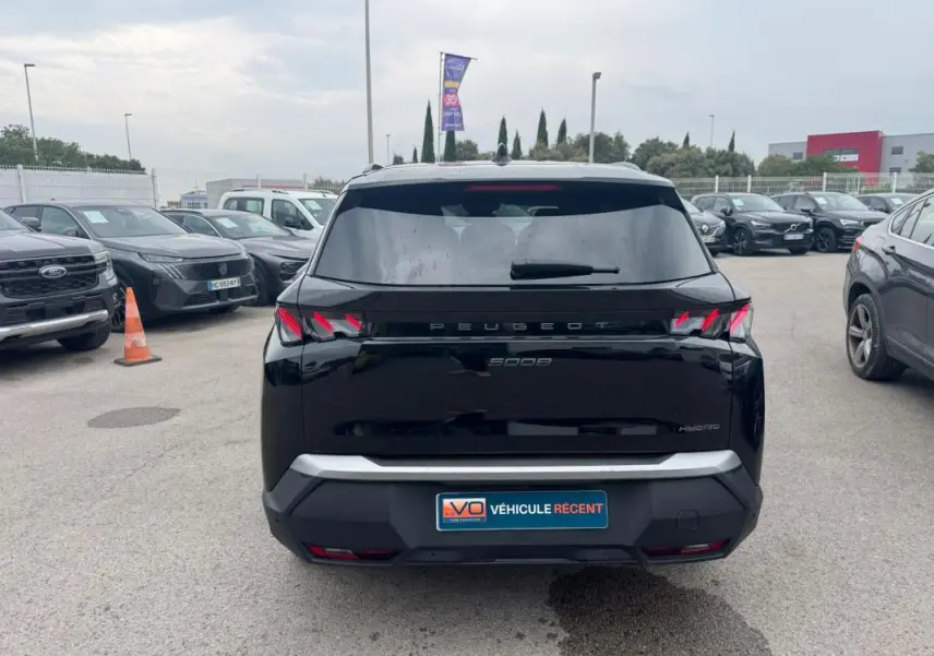 Vue arrière d’un Peugeot 5008 Hybrid noir 2025 avec feux arrière distinctifs en forme de griffes et plaque "Véhicule récent".