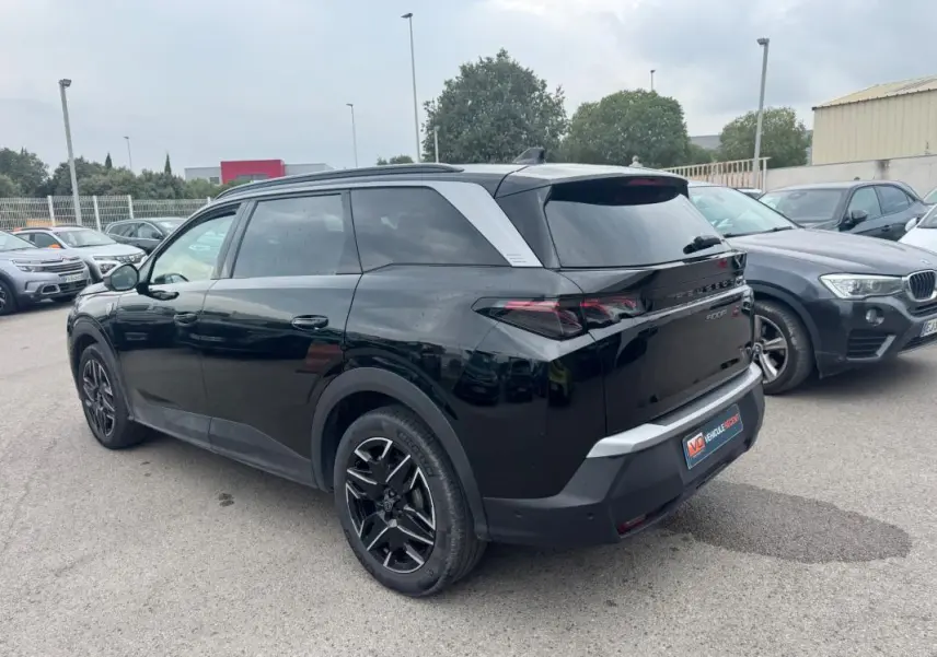Peugeot 5008 Hybrid noir vue 3/4 arrière droit, avec jantes alliage noires et barres de toit visibles.