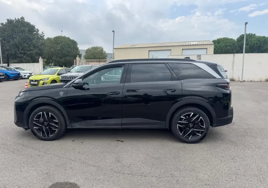Peugeot 5008 Hybrid noir vue de profil côté gauche, avec jantes alliage noires et barres de toit visibles.