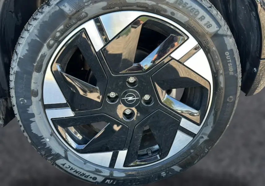 Gros plan sur la jante alu noire et argentée d’un Opel Mokka Electric 156 gs bleu, avec logo Opel au centre.