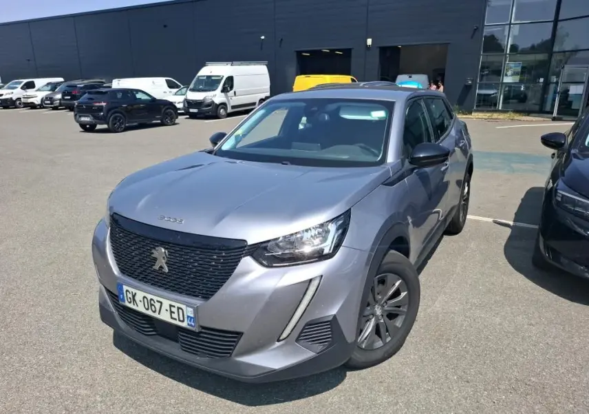Peugeot 2008 gris Artense vue 3/4 avant droit, avec calandre noire et jantes foncées sur parking extérieur.
