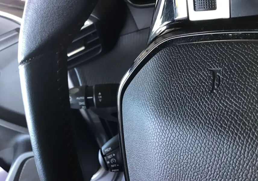 Gros plan sur le volant en cuir noir du Peugeot 2008 1.5 BlueHDi 110, montrant les commandes au volant et la texture du cuir.
