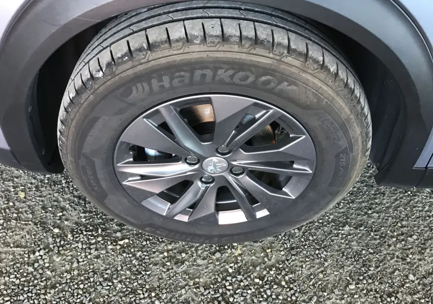 Gros plan sur la roue avant gauche d’un Peugeot 2008 gris Artense avec jante alliage et pneu Hankook.