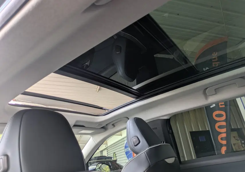 Vue intérieure du toit panoramique ouvert du Citroën C5 Aircross hybride 2026 avec sièges noirs visibles.
