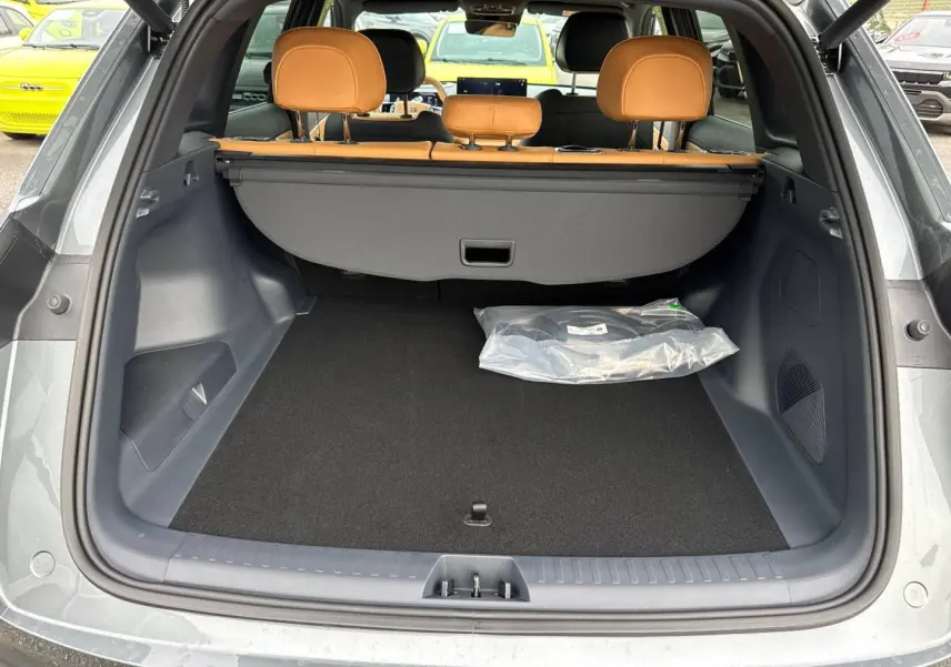 Coffre ouvert vu de l'arrière d'un Geely STARRAY gris volcanic avec banquette cuir camel et cache-bagages.