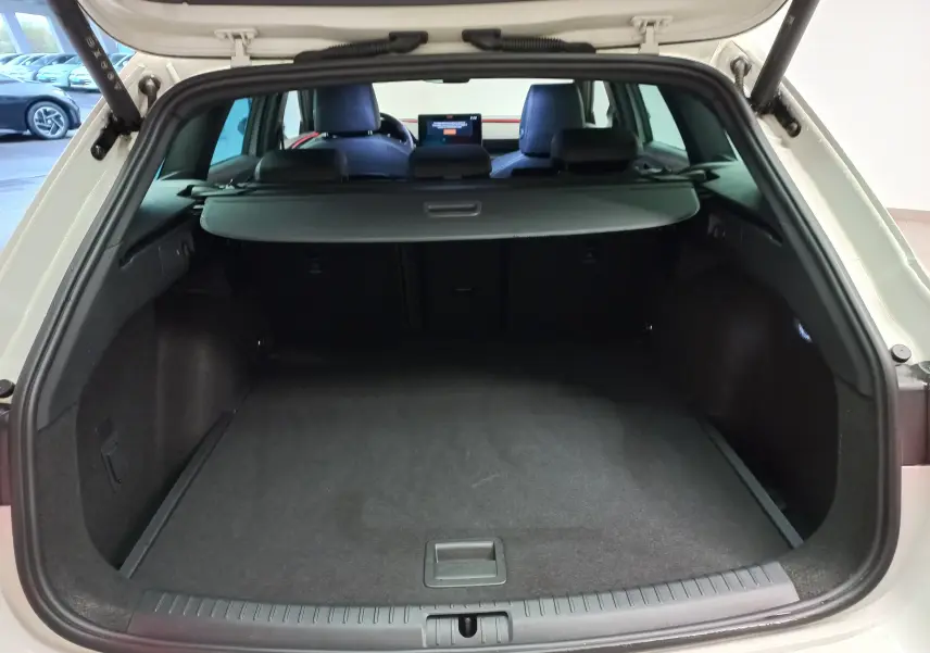 Coffre ouvert vu de l’arrière d’une CUPRA LEON ST 1.5 eTSI gris Taiga avec cache-bagages et intérieur noir.