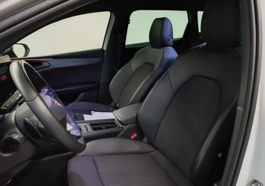 Vue intérieure côté conducteur de la CUPRA LEON ST 1.5 eTSI 150 DSG7, sièges noirs et volant cuir perforé.