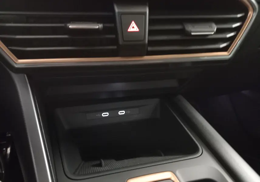 Gros plan intérieur sur la console centrale du CUPRA LEON ST 2025, avec prises USB-C et cadre cuivré autour des aérateurs.