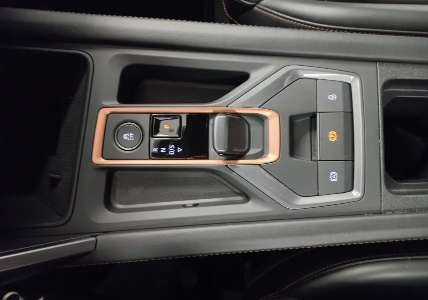 Gros plan sur la console centrale du CUPRA LEON ST 1.5 eTSI 150 DSG7 avec sélecteur de vitesse et cadre cuivré.