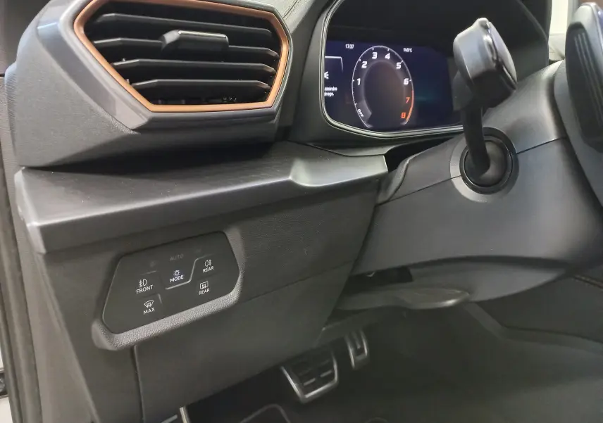 Détail intérieur côté gauche du tableau de bord de la CUPRA LEON ST 1.5 eTSI 2025 avec commandes d’éclairage et cadre d’aération cuivré.