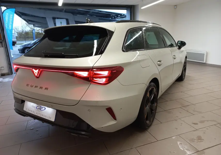 Vue 3/4 arrière droite d'une CUPRA Leon ST gris Taiga avec feux arrière LED et jantes alliage 18'' cuivrées.