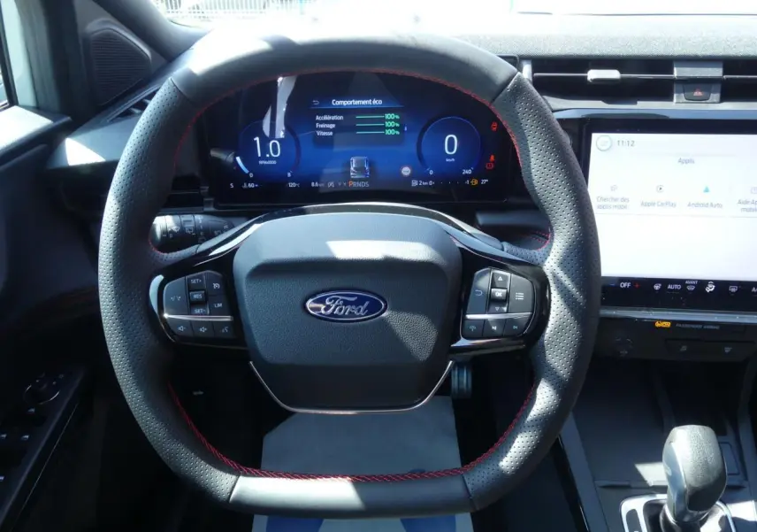 Vue rapprochée du volant perforé avec surpiqûres rouges et tableau de bord numérique du Ford Puma 2025 ST-Line.