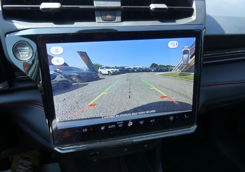 Écran tactile central affichant la caméra de recul dans un Ford Puma gris métallisé, avec commandes climatisation et bouton start visible.