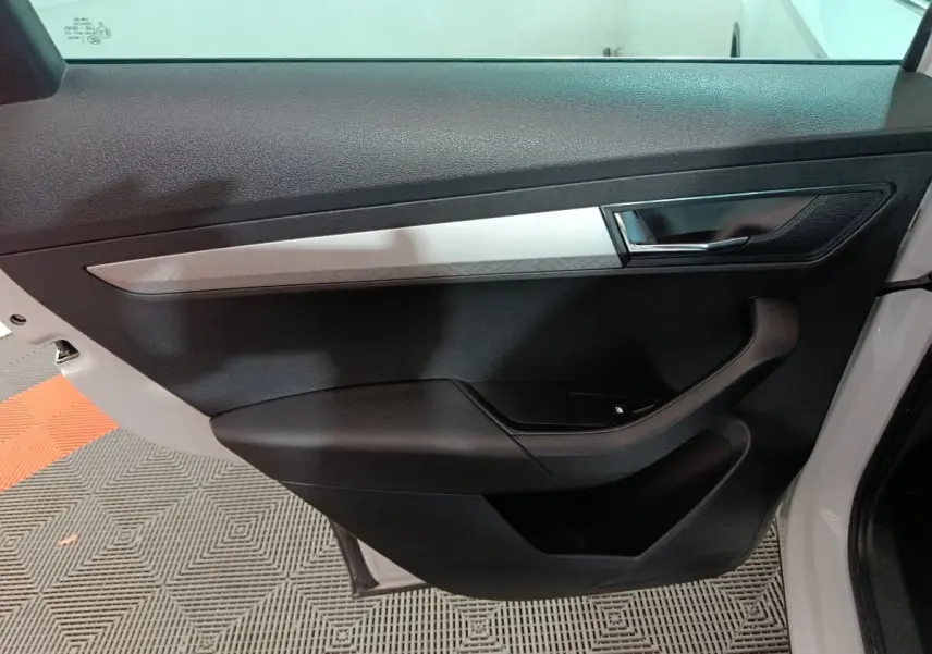 Vue côté gauche de la porte intérieure noire et grise du Skoda Karoq 2024 avec poignée et commande de fenêtre électrique.