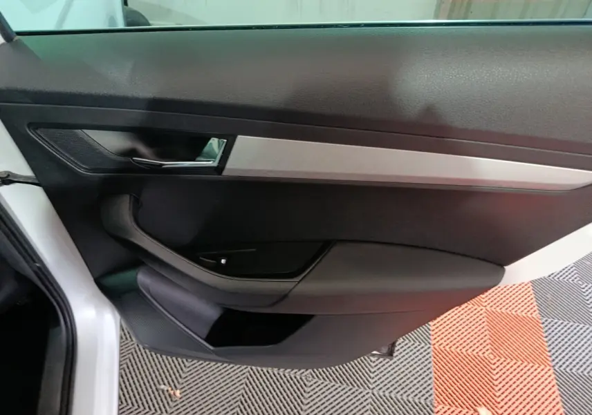 Vue intérieure côté gauche de la porte avant d'une Skoda Karoq 2024, avec garniture noire et insert argenté.