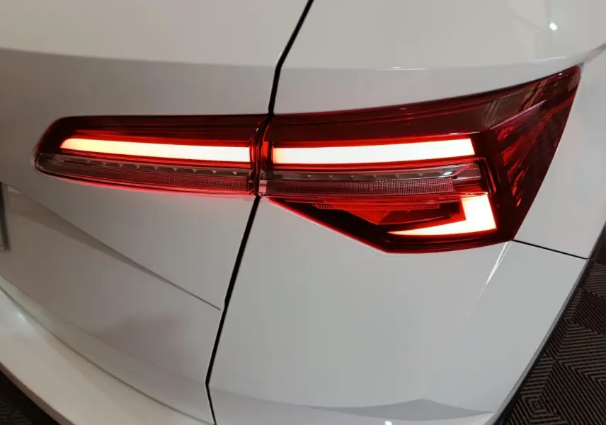 Feu arrière droit allumé d'un SKODA KAROQ blanc 2024, mettant en valeur son design LED moderne.