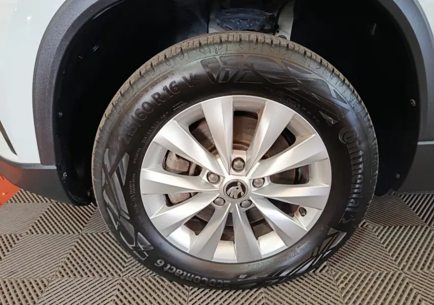 Gros plan sur la roue avant gauche argentée d'un Skoda Karoq 2024 avec carrosserie blanche visible en arrière-plan.