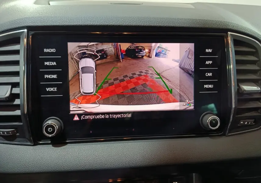 Écran tactile central montrant la caméra de recul avec trajectoire assistée dans un Skoda Karoq 2024 gris.