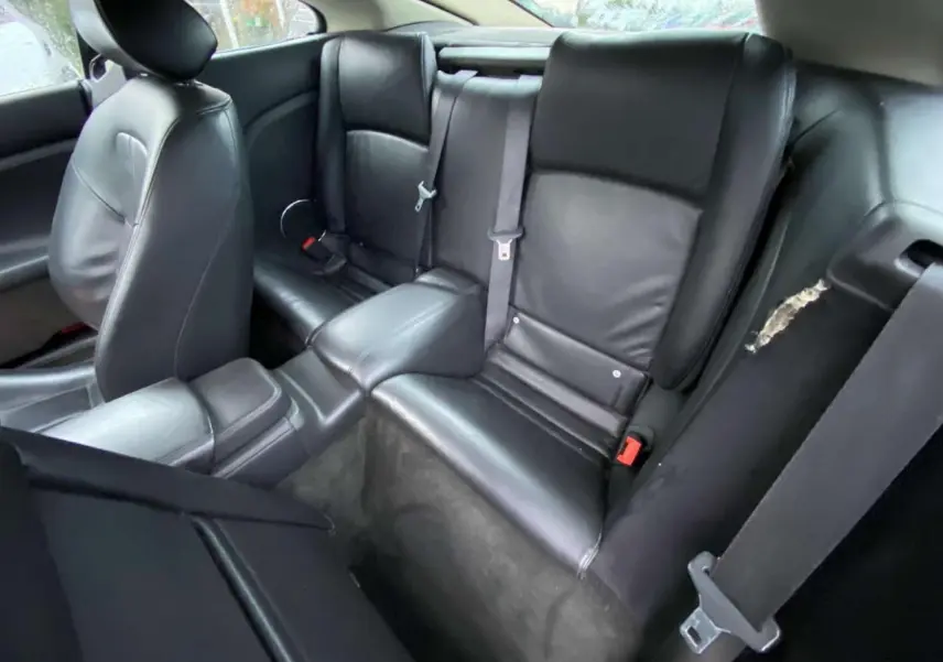 Intérieur arrière du coupé Jaguar XK 4.2i V8 2009, sièges cuir noir vus en plongée côté droit.