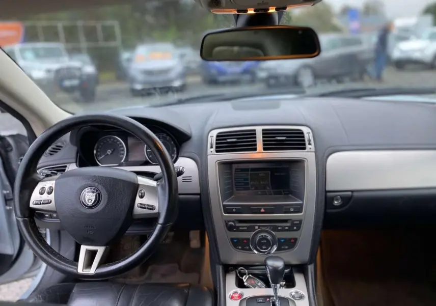 Intérieur du Jaguar XK 2009, vue du tableau de bord et volant en cuir noir avec console centrale et levier de vitesse automatique.