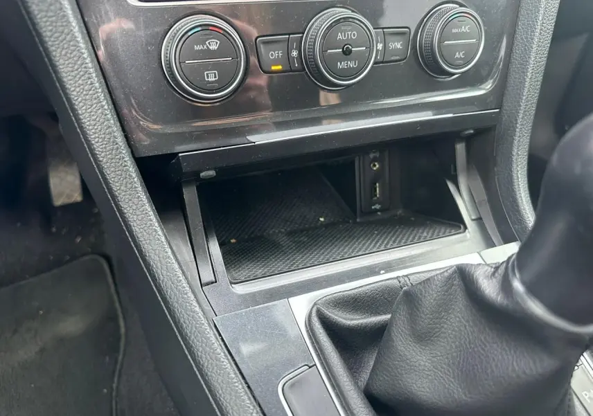 Gros plan sur la console centrale intérieure noire de la Volkswagen Golf VII avec boîte manuelle et commandes climatisation.