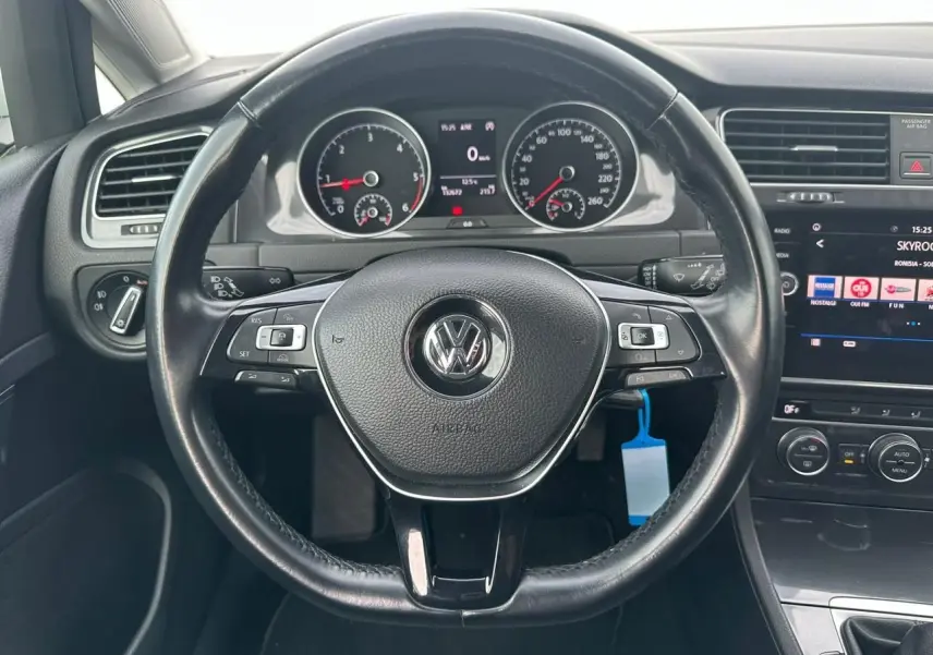 Vue intérieure centrée sur le volant en cuir noir d'une Volkswagen Golf VII avec tableau de bord et écran tactile.