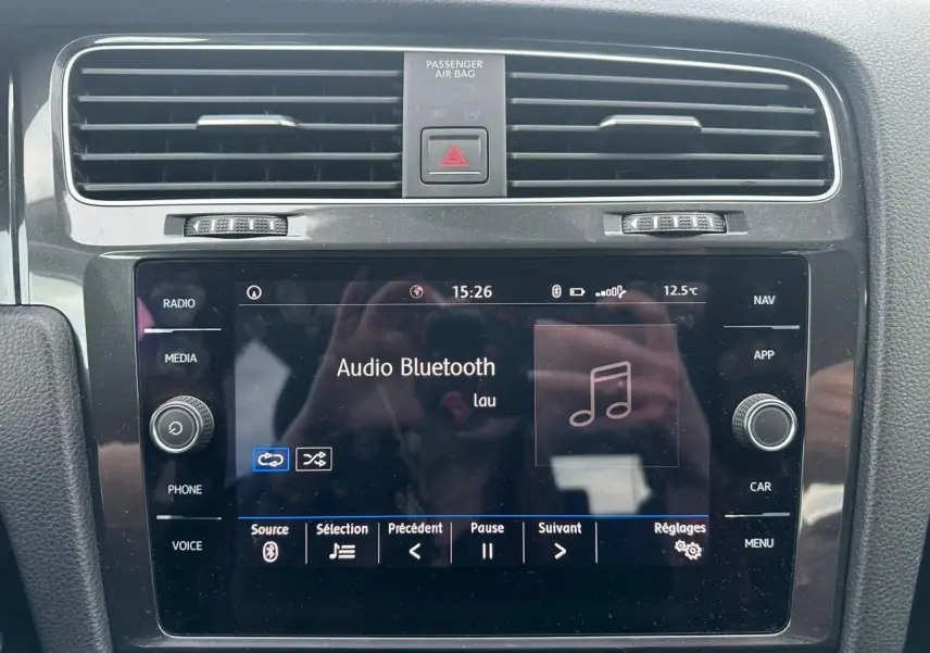 Vue rapprochée de la console centrale noire de la Volkswagen Golf VII avec écran tactile affichant l'audio Bluetooth.