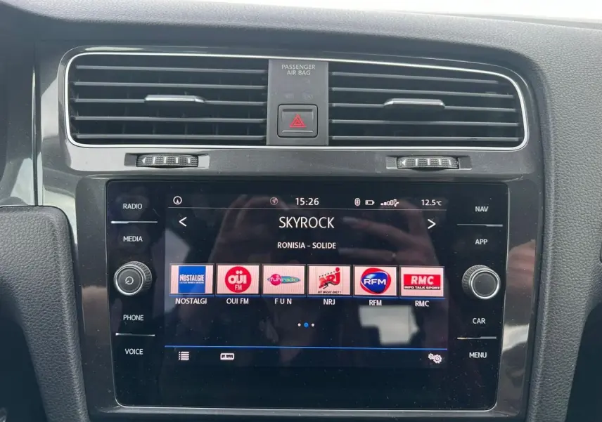 Vue rapprochée de la console centrale de la Volkswagen Golf VII blanche, affichant l'écran tactile multimédia.