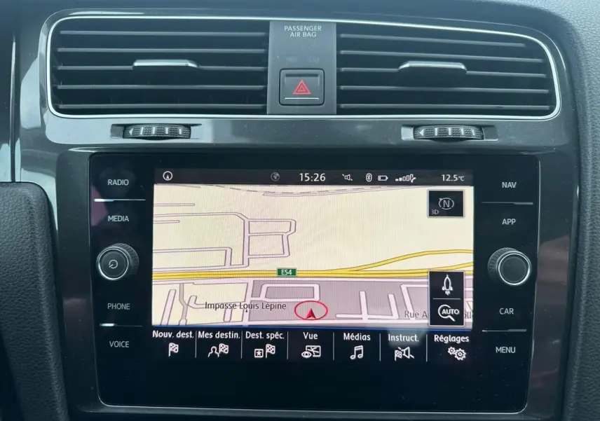 Vue rapprochée de l’écran tactile central noir affichant la navigation GPS dans une Volkswagen Golf blanche de 2018.