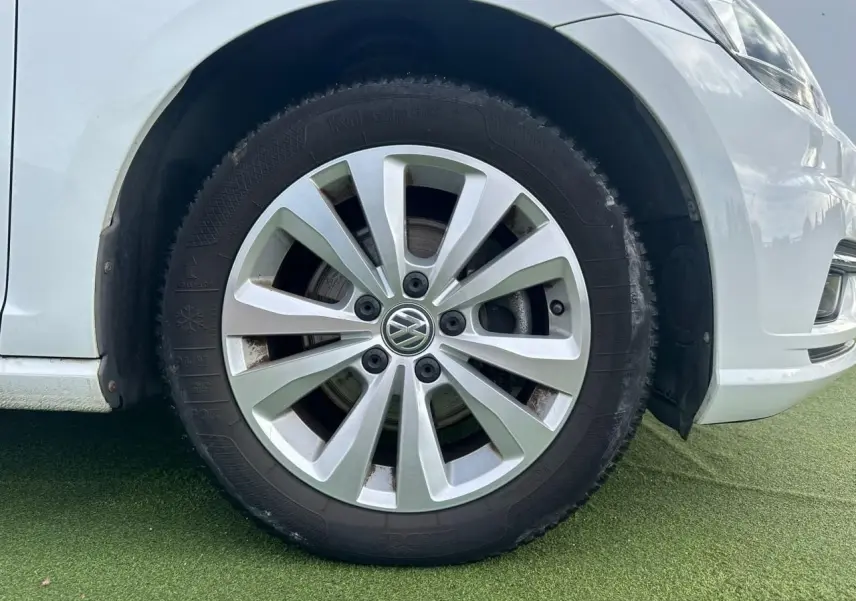 Gros plan sur la roue avant droite d'une Volkswagen Golf blanche, jante alliage 16 pouces au design moderne.
