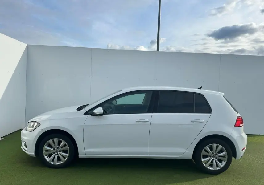 Profil droit d'une Volkswagen Golf VII blanche de 2018, avec jantes alliage 16 pouces et vitres teintées.