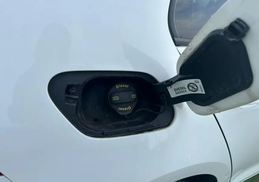 Gros plan sur la trappe à carburant ouverte d’une Volkswagen Golf blanche, bouchon diesel visible côté arrière droit.
