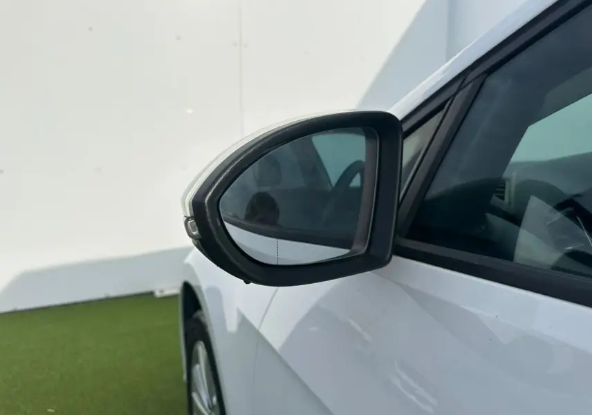 Vue rapprochée du rétroviseur extérieur droit d'une Volkswagen Golf VII blanche, avec partie avant et vitre latérale visibles.