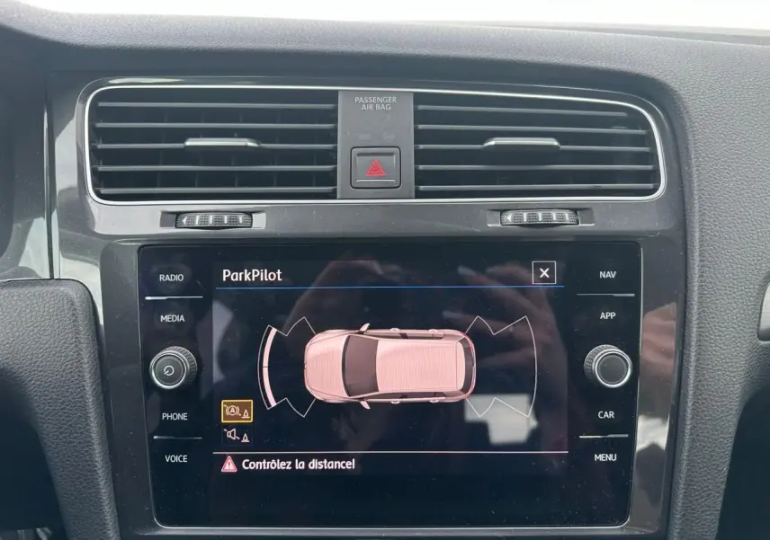 Écran tactile central de la Volkswagen Golf VII blanc montrant l'alerte ParkPilot pour aide au stationnement.