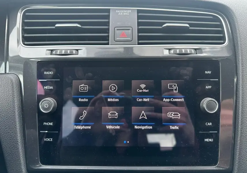 Écran tactile central de la Volkswagen Golf VII blanc, vue frontale du système multimédia avec commandes autour.
