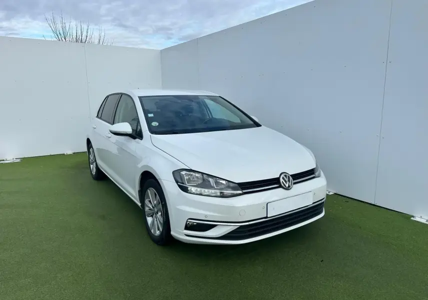 Volkswagen Golf VII blanche vue 3/4 avant droite sur sol vert avec pare-chocs et phares nets.