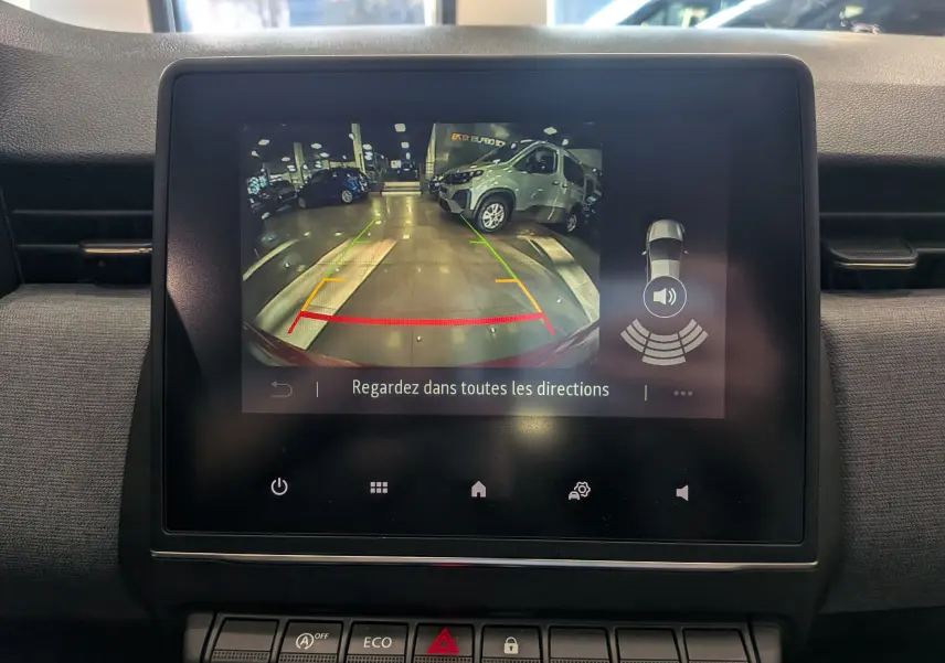 Écran central de la Renault Clio V Orange Valencia montrant l’affichage de la caméra de recul avec guidage et alertes sonores.
