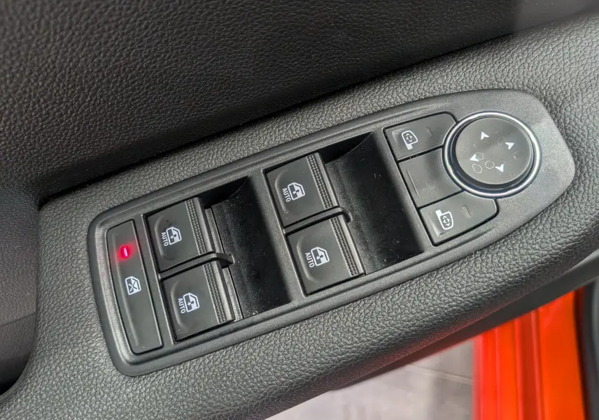 Gros plan sur les commandes des vitres et rétroviseurs côté conducteur d'une Renault Clio V Orange Valencia 2024.