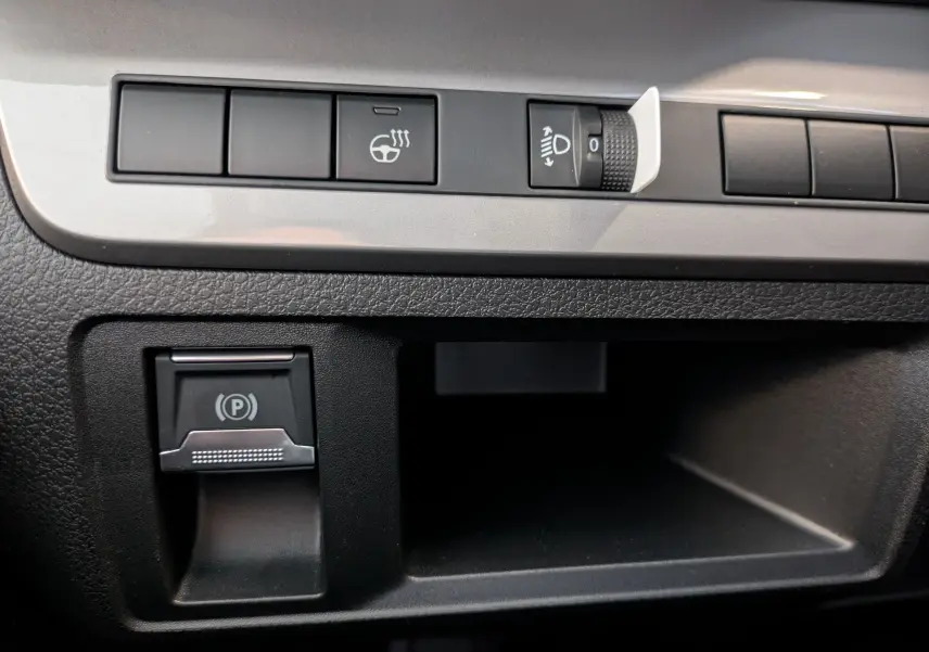 Gros plan sur les commandes noires du tableau de bord du Peugeot Traveller 2026, incluant le frein à main électrique.