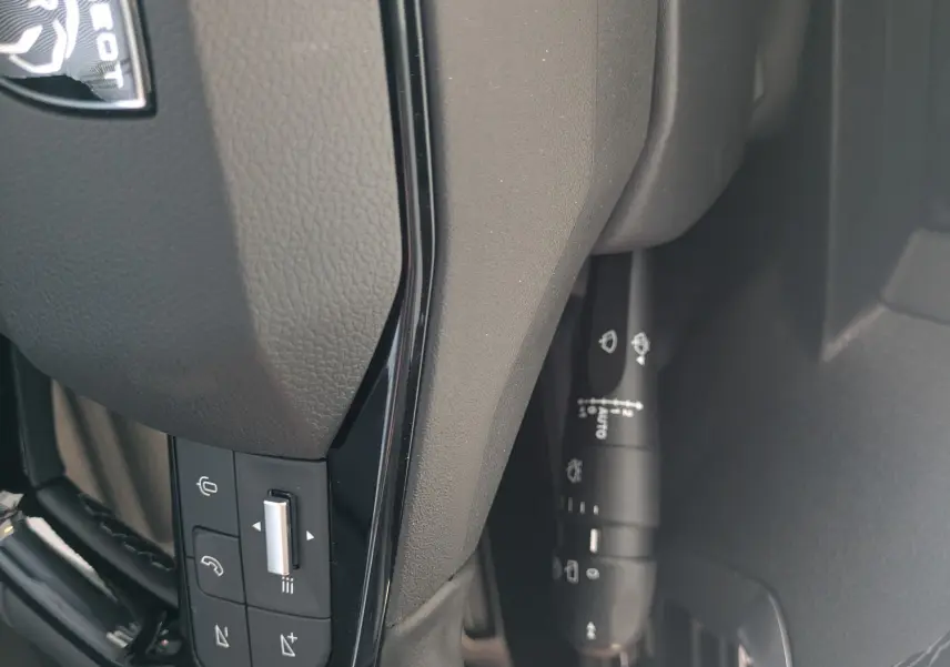 Gros plan sur le volant cuir noir du Peugeot Traveller 2026 avec commandes intégrées et logo Peugeot visible.
