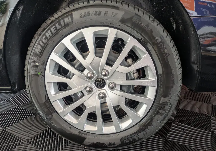 Gros plan sur la roue avant gauche du Peugeot Traveller noir 2026, avec jante argentée et pneu Michelin visible.